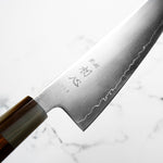 Close-up of a Japanese knife with engraved text on a white background