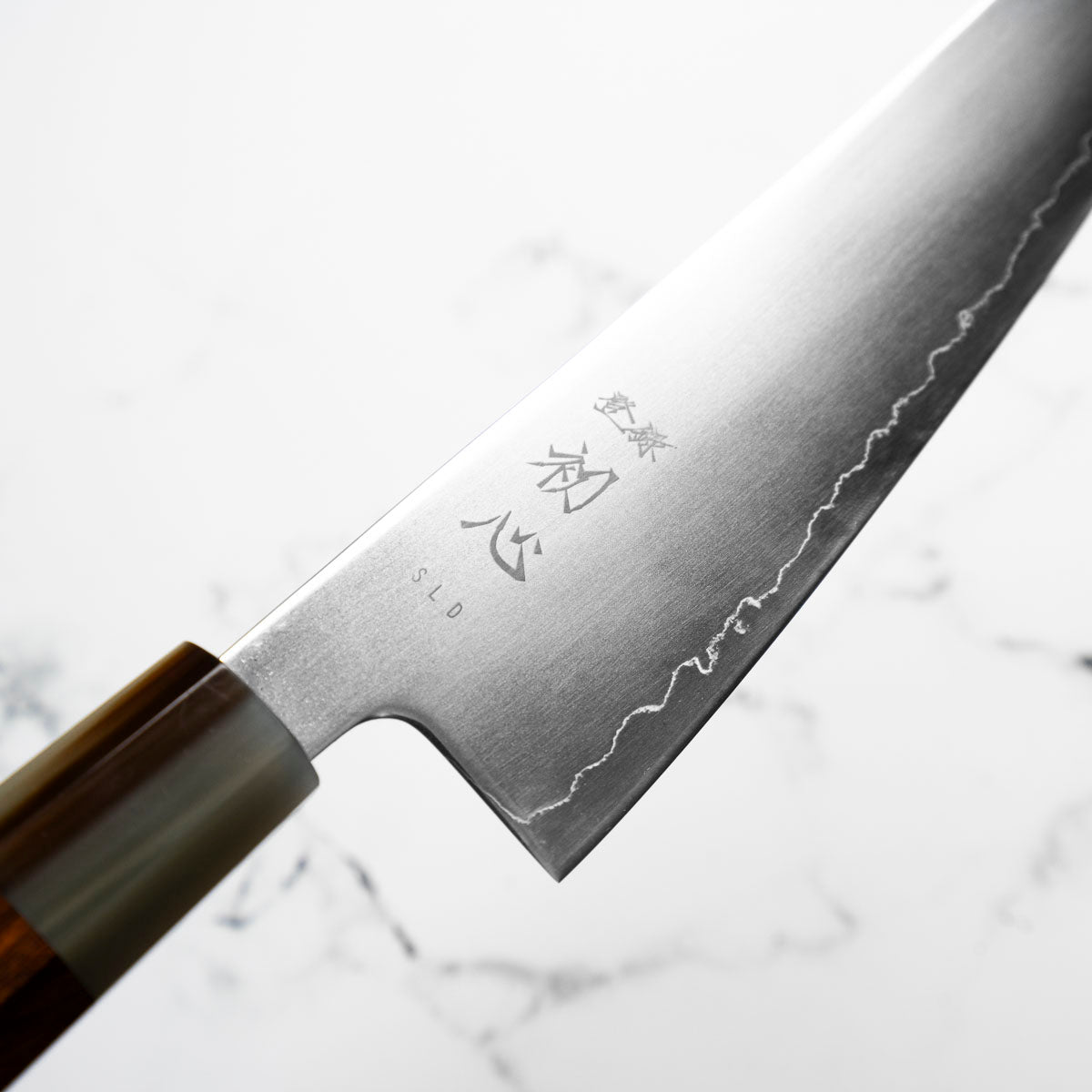 Close-up of a Japanese knife with engraved text on a white background